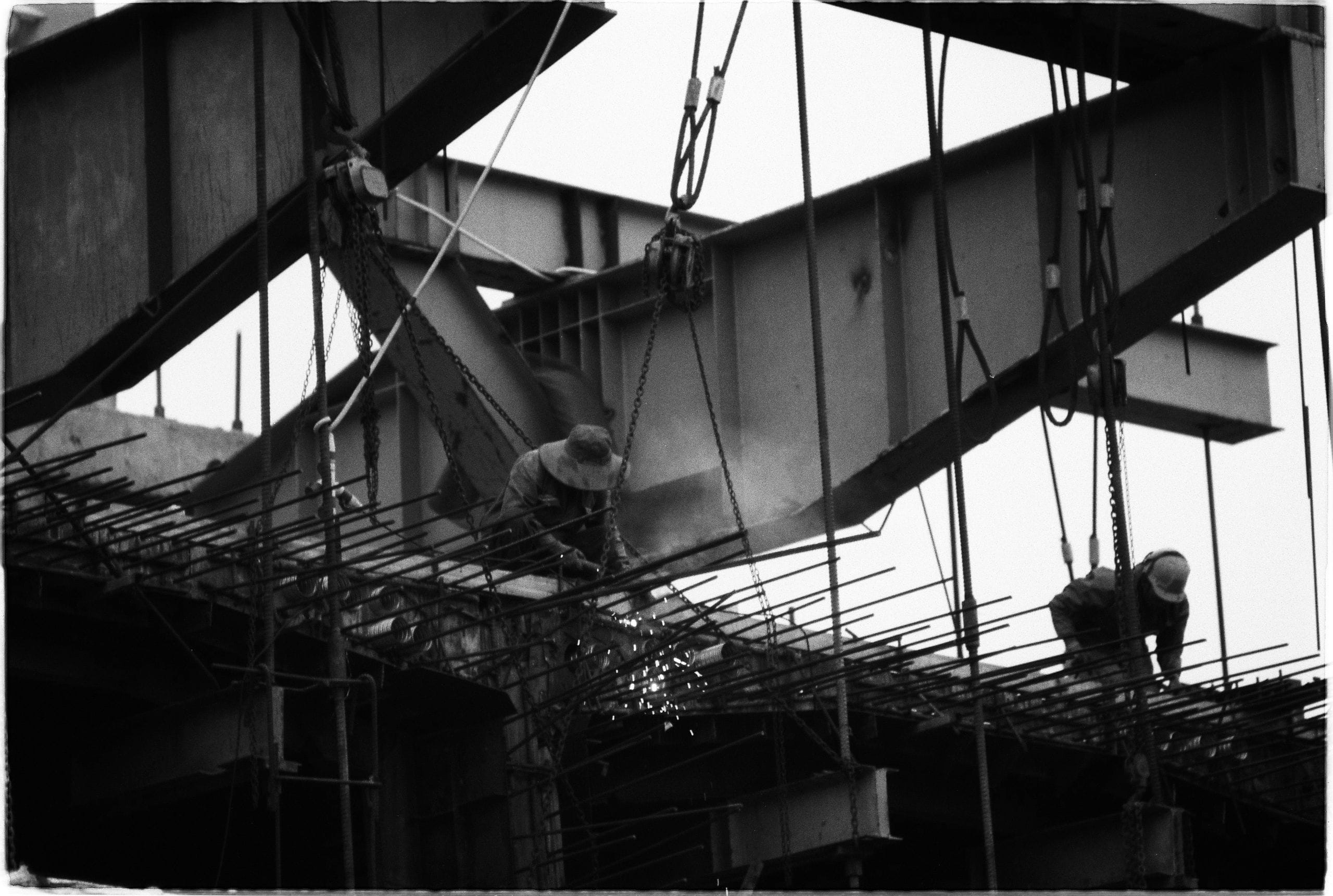 Monteurs soudant une structure en acier sur un chantier de grande hauteur, en noir et blanc